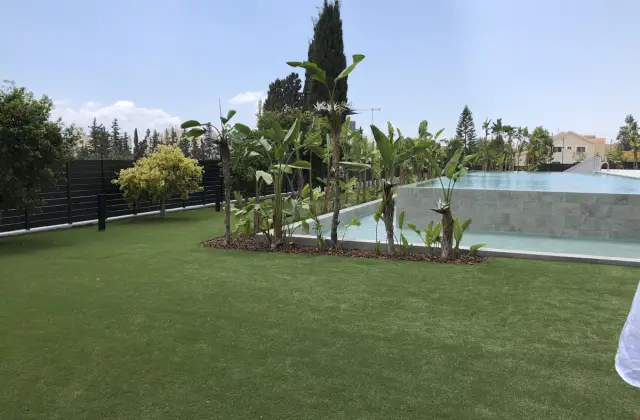Jardim com relva artificial e palmeiras ao lado de uma piscina
